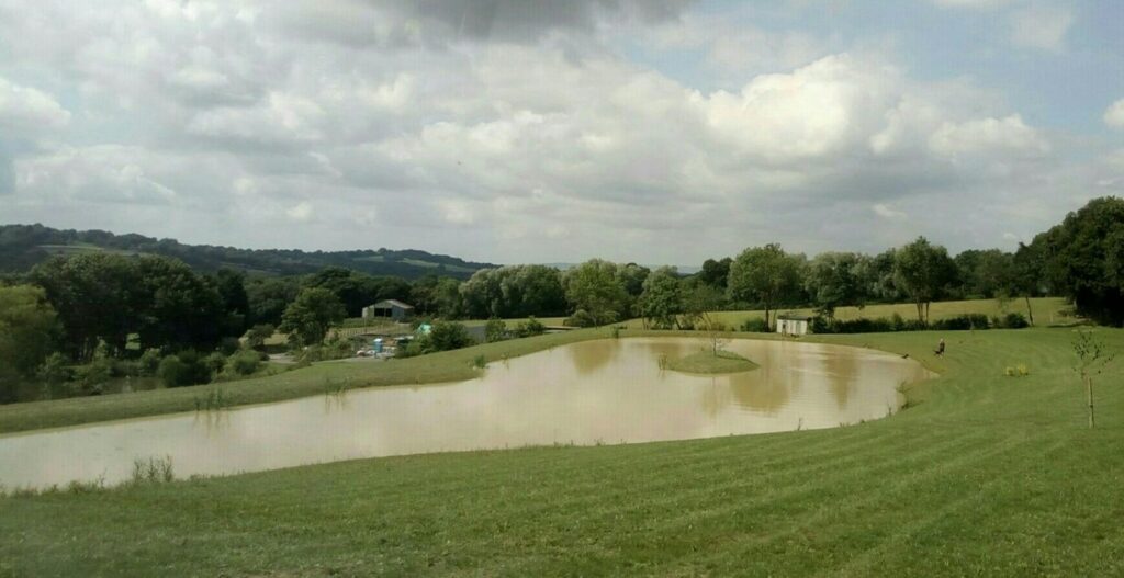 Spring-fed lake at Hastingford Fishery in East Sussex, where the shepherd's huts have a wild swimming pool on site